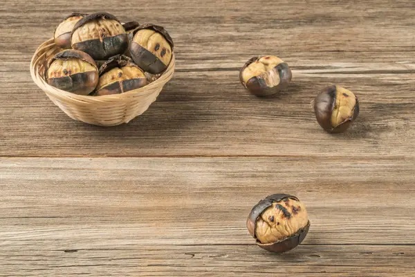 Castañas asadas en una cesta sobre una mesa de madera — Foto de Stock