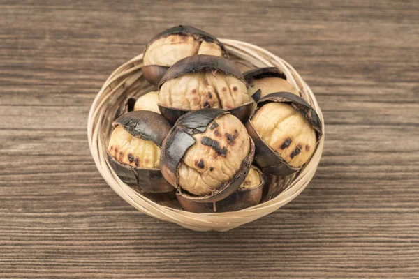 Geröstete Kastanien in einem Korb auf einem Holztisch — Stockfoto