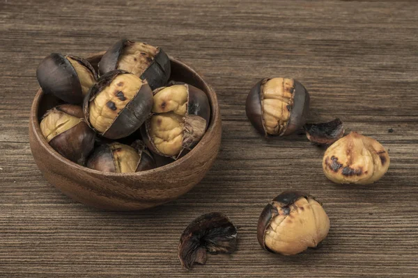 Geröstete Kastanien in einer Schüssel auf einem Holztisch — Stockfoto