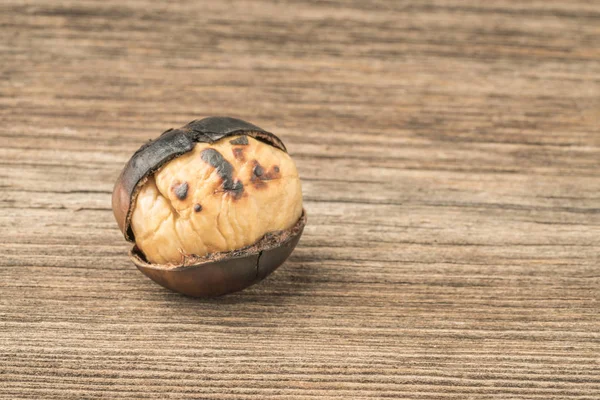 Closeup of a roasted chestnut on a wooden table — 스톡 사진