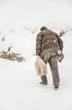 Karda yürürken çanta taşıyan bir adam