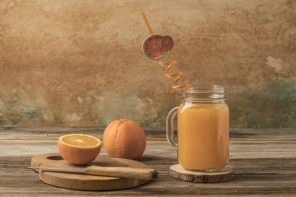 Glass of fresh orange juice and oranges on cutting board — Stock Photo, Image