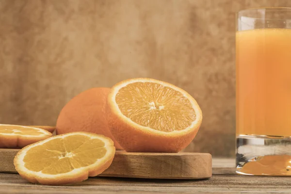 Glas frischer Orangensaft und Orangen auf Schneidebrett — Stockfoto