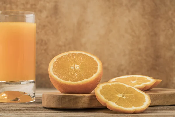 Glas frischer Orangensaft und Orangen auf Schneidebrett — Stockfoto