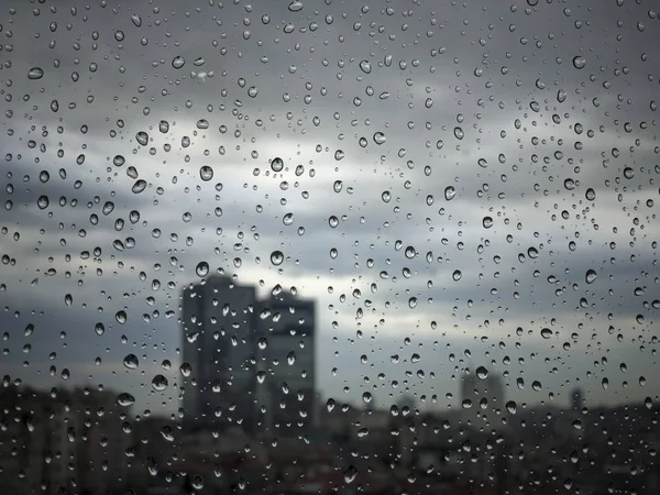 Gotas de lluvia en el cristal de la ventana contra vista a la ciudad — Foto de Stock