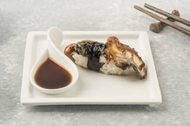 Beyaz tabakta yılan balığı olan Unagi Nigiri. Soya soslu suşi.