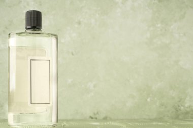 Yeşilin üzerinde boş bir etiket ve kopyalama alanı olan bir parfüm şişesi.