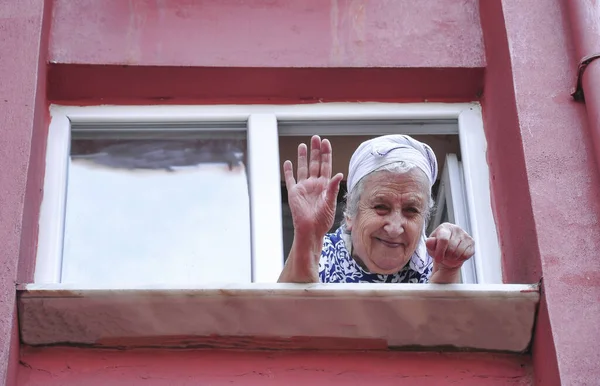 Een Gelukkige Oudere Vrouw Zwaait Met Haar Hand Uit Het — Stockfoto