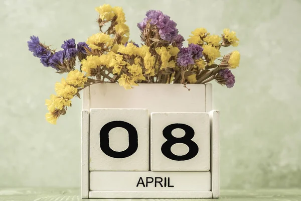 コピースペース付き緑の背景に花で飾られた4月のキューブカレンダー — ストック写真
