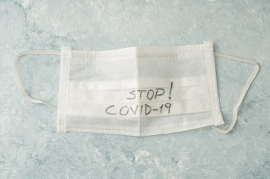 Mavi üzerinde covid-19 Corona virüsüne karşı tek kullanımlık beyaz bir sağlık maskesinin fotokopi alanı ile yakın plan görüntüsü.