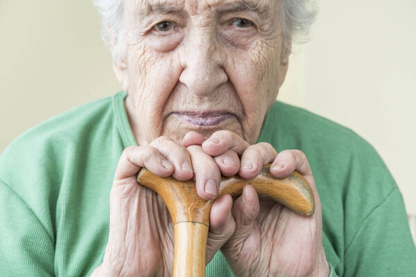 closeup of a senior woman leaning on a wooden cane