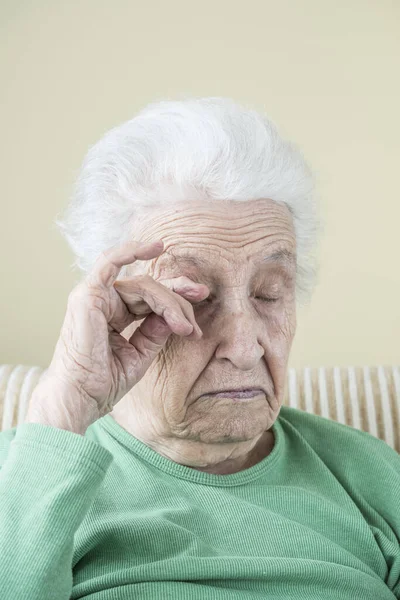 a senior woman touching her wrinkled face and eye that is risky for corona virus contamination