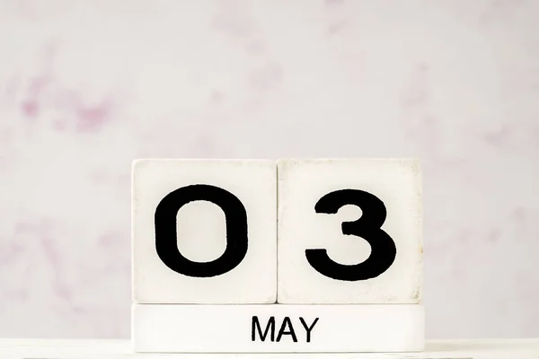 White cube calendar for May against soft pink background with copy space