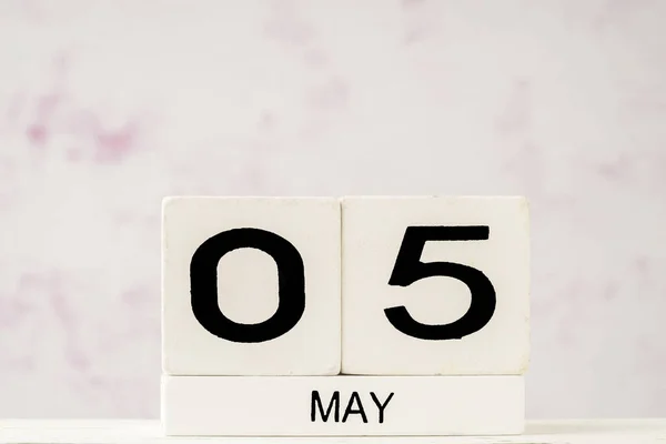White cube calendar for May against soft pink background with copy space