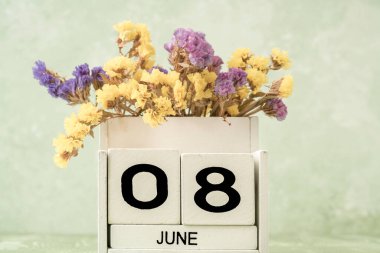 Haziran için beyaz küp takvimi kopyalama alanı ile yeşil arkaplan üzerindeki çiçeklerle dekore edilmiş