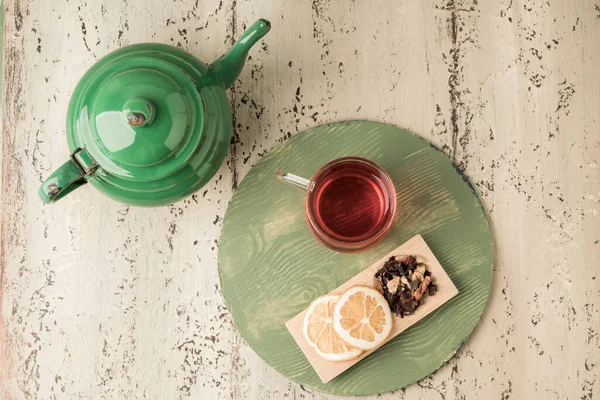 a glass of herbal tea and vintage enamel teapot on a wooden table