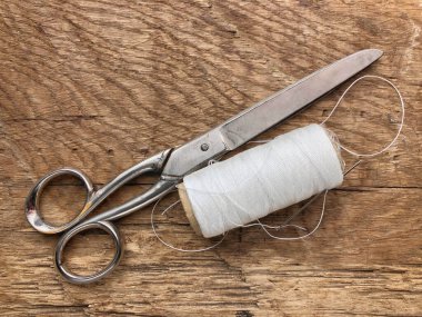 Makas ve makara beyaz iplik, ahşap bir masada ip