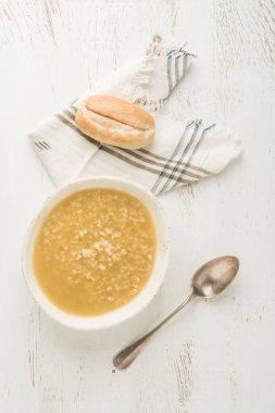 Bir kase kırmızı mercimek çorbası ve ekmek ahşap bir masada.