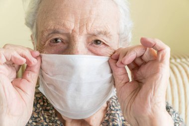 Kendini salgın 19 virüsünden korumak için tıbbi maske takan yaşlı bir kadın.