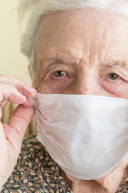 Kendini salgın 19 virüsünden korumak için tıbbi maske takan yaşlı bir kadın.