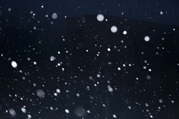Lumihiutaleet pimeällä taivaalla — kuvapankkivalokuva
