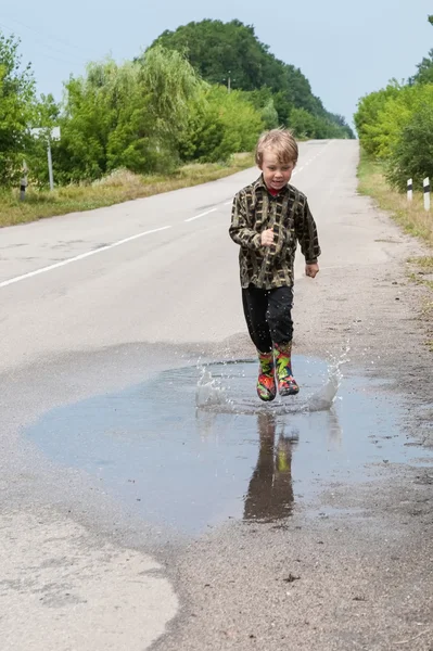 Boy jumping in puddles — Stock Photo, Image