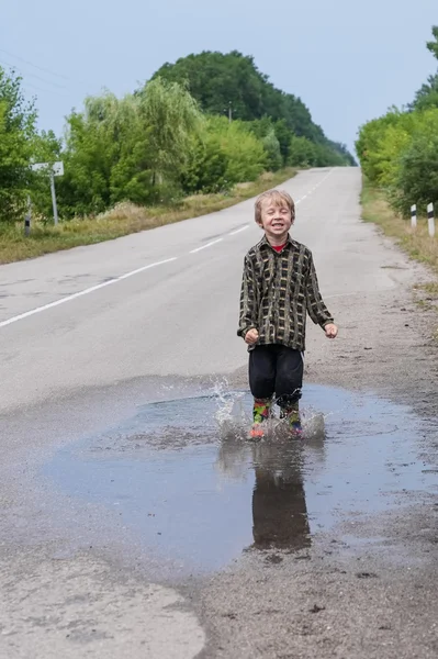 Boy jumping in puddles — Stock Photo, Image