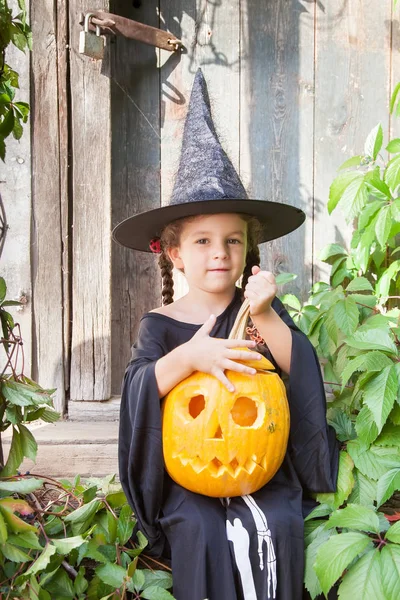 Kleine Hexe mit Halloween-Kürbis Stockfoto