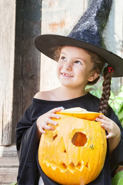Kleine Hexe mit Halloween-Kürbis Stockbild