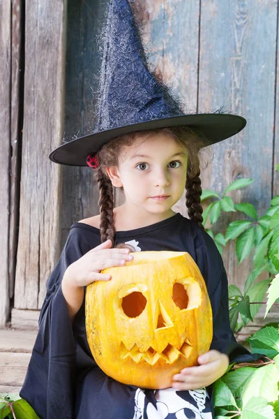 Kleine Hexe mit Halloween-Kürbis lizenzfreie Stockbilder