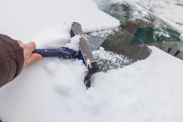 Cleaning windshield from snow with scraper — Stock Photo, Image