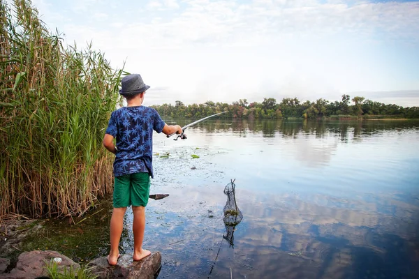 Ragazzo con una canna da pesca cattura un pesce — Foto Stock