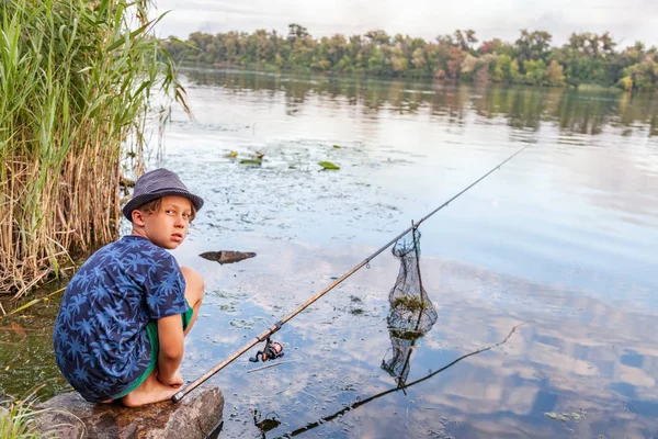 Menino com uma vara de pesca pega um peixe — Fotografia de Stock