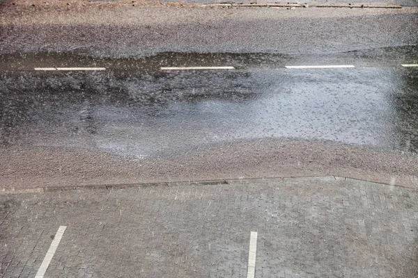 Краплі сильного дощу падають на міську вулицю під час сходу — стокове фото