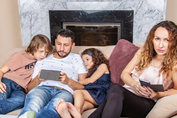 Papa mit Kindern schaut Videos auf dem Smartphone, Mama im Stuhl in der Nähe — Stockfoto