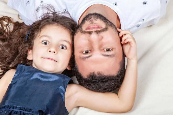 Otec a dcera leží od hlavy k patě na posteli — Stock fotografie