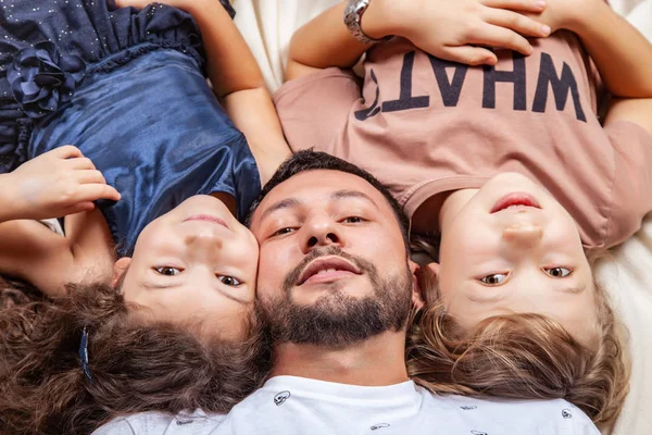 Otec leží uprostřed mezi svými dětmi. — Stock fotografie