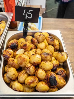 Sokak yemeği festivalinde paslanmaz çelik tepside ızgara patates, yakın çekim manzarası.