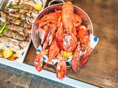 Galvanizli metal bir leğende kızartılmış ıstakoz ve yenmeye hazır kızarmış balık.