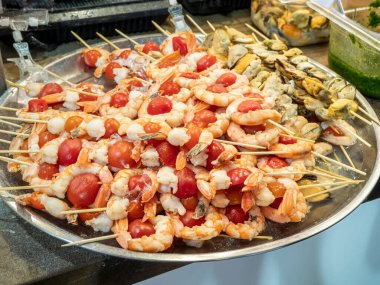 Izgara deniz ürünleri, domatesli karides şişleri ve tahta çubuklarda midye ızgarası.