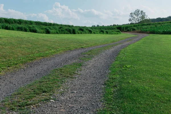 Lunga strada di ghiaia che attraversa terreni agricoli — Foto Stock