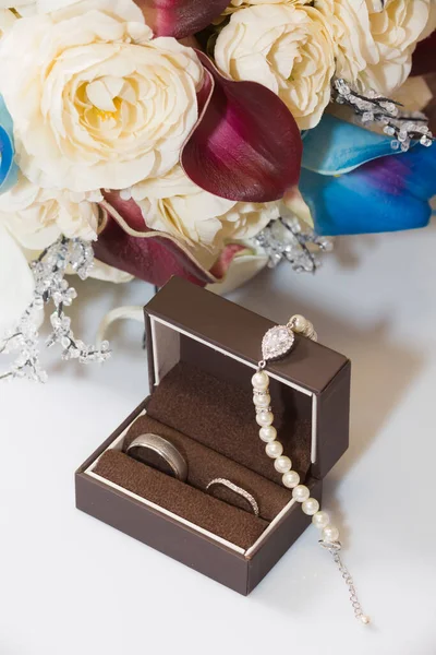 带珠宝和新娘花束的结婚戒指盒中的婚戒 — 图库照片