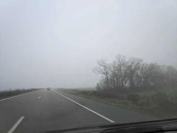 in a car in cloudy weather. rain and fog on the road