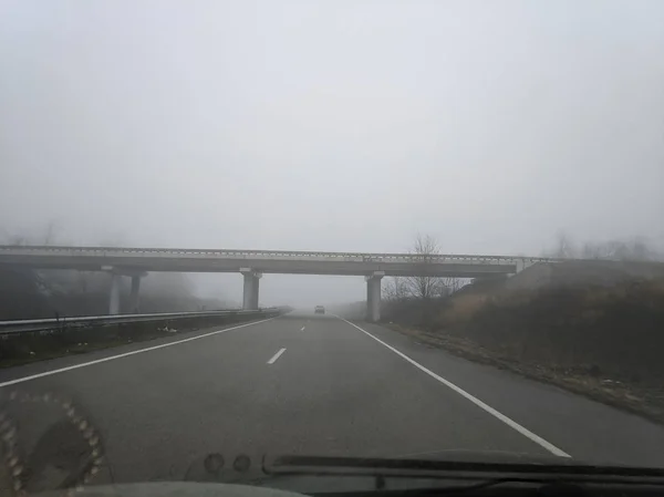 in a car in cloudy weather. rain and fog on the road