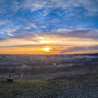 Şehrin üzerinde gün doğumu. Fabrika bacası duman ve güneş