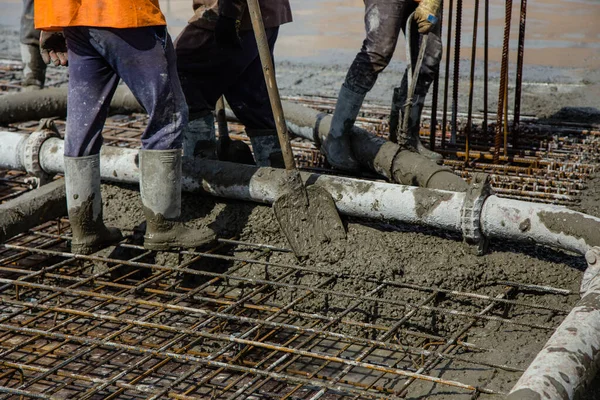 Pouring concrete on a construction site. Concrete is fed from the concrete mixer to the concrete pump, and the worker controls the flow on his floor