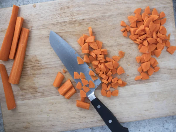 Нарезание моркови на доске для резки — стоковое фото