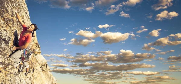 Rock climber clinging to a cliff. Stock Picture