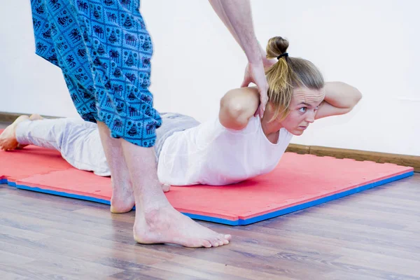 Antrenör kızın yoga pozisyonunu ayarlar.