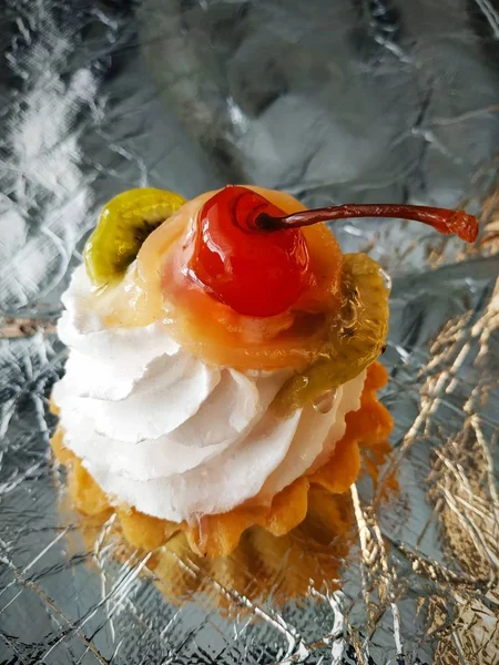Tatlı kek. Üstünde krema, meyve ve kiraz olan bir sepet.